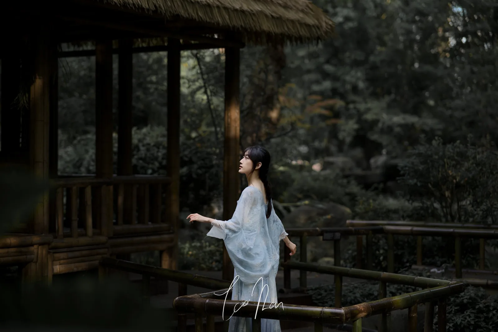 木亭与树影之间，穿浅色衣服的人静静站立